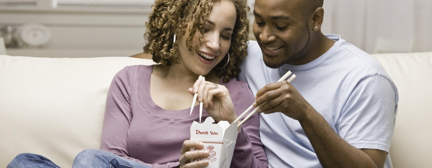 a man and a woman sitting on a couch and holding a box